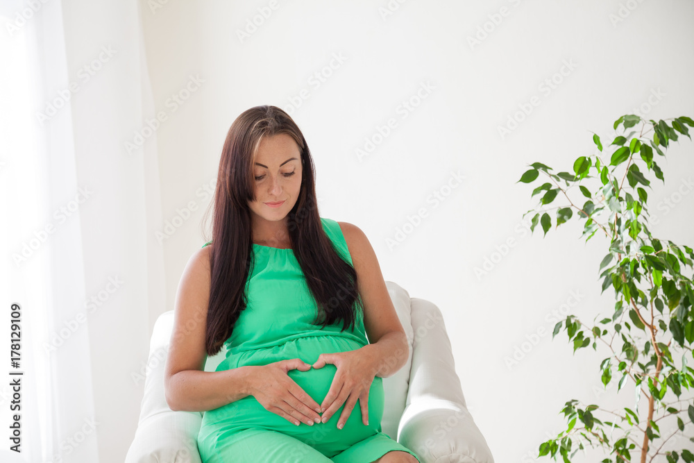 a pregnant woman before childbirth sits in white couch a pregnant woman before childbirth sits in white couch