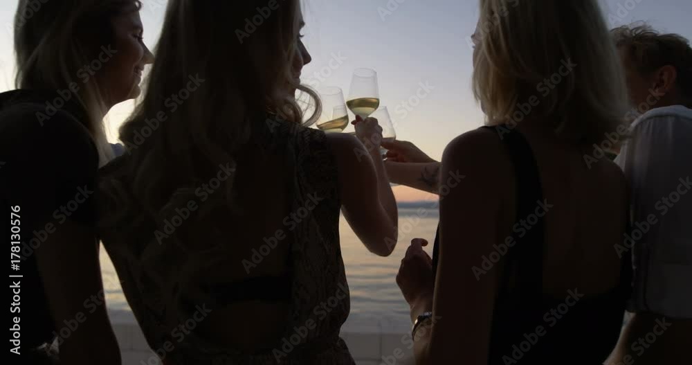 Back View of Group Of Five Young People Clinking Champagne Glasses on a Yacht and Admiring Seascape Sunset. Shot on RED Epic 4K UHD Camera.