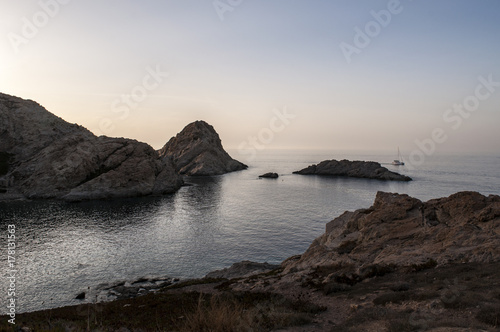 Corsica, 30/08/2017: una barca a vela al tramonto sul Mar Mediterraneo vista dalla scogliera dell'Isola della Pietra, promontorio disabitato di Isola Rossa, famosa città dell'Alta Corsica