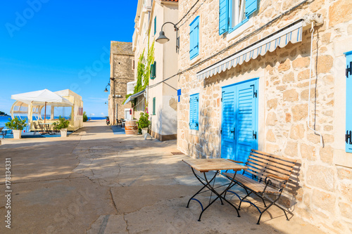 Small table in front of coastal restaurant with blue windows old town of Primosten, Dalmatia, Croatia photo