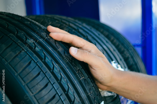 Close up of person checking examining car tyre on the shelf abstract transportation background. Automobile warehouse business, factory production. Protector surface texture