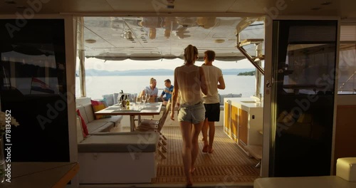Group of Successful Young People Join Others in the Stern of the Yacht with Cocktails. In the Background Calm Sea and Islands. Shot on RED Epic 4K UHD Camera. photo