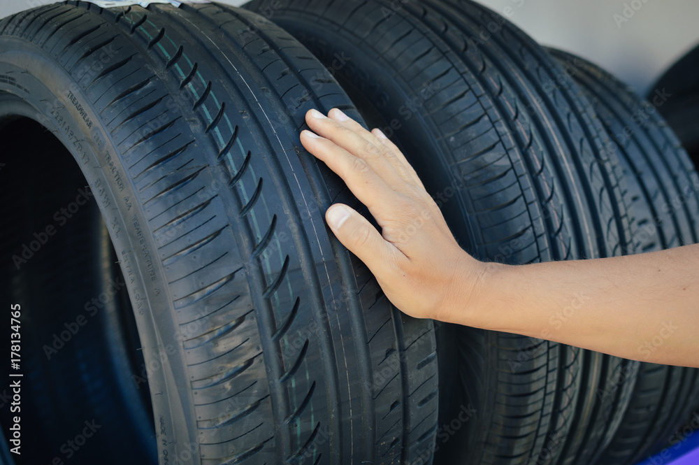 Close up of person checking examining car tyre on the shelf abstract transportation background. Automobile warehouse business, factory production. Protector surface texture