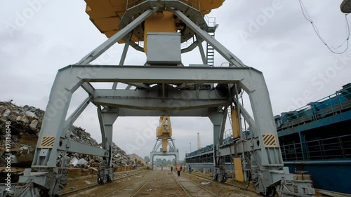 huge industrial crane are standing in a wrecking yard of a scrap metal processing plant in cloudy weather in summer day photo