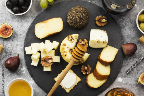 Snacks with wine - various types of cheeses, figs, nuts, honey, grapes on a gray background. Top view. Food background