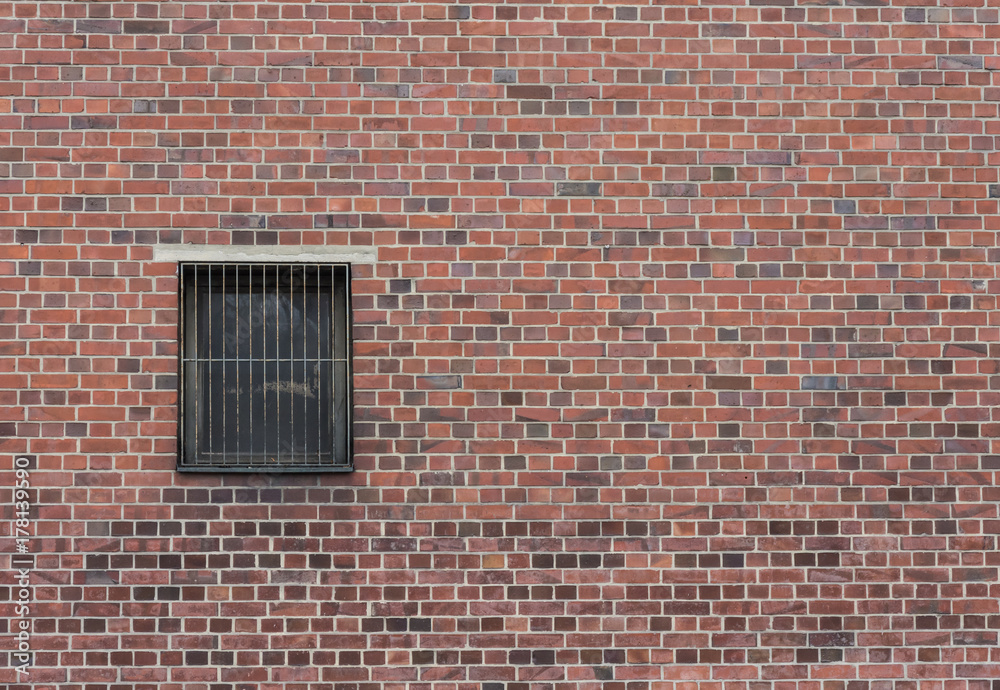 Rote Backsteinwand mit einem vergitterten Fenster Rote Backsteinwand mit einem vergitterten Fenster