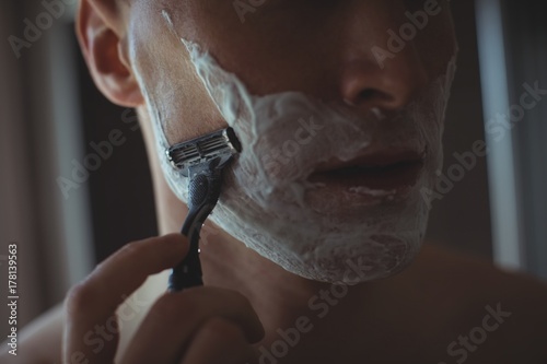 Man shaving his beard with razor