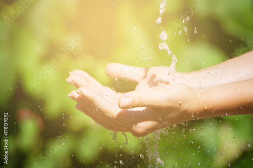 Woman washing hand outdoors. Natural drinking water in the palm. Young hands with water splash, selective focus. Instagram