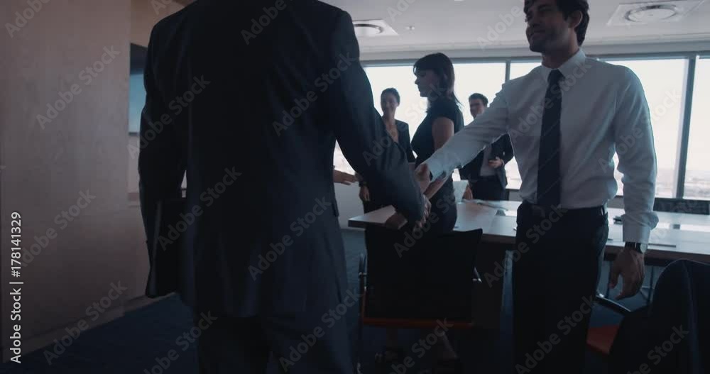 Businesspeople entering a conference room for business meeting. Executives arriving for meeting and shaking hands with colleagues.