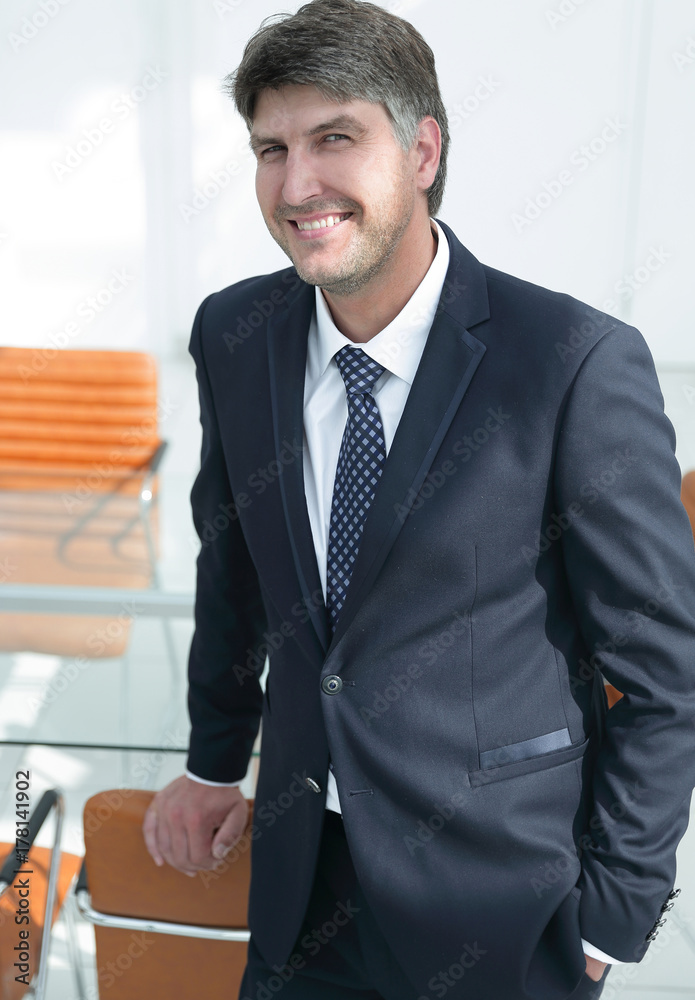 successful businessman standing by the desk. successful businessman standing by the desk.