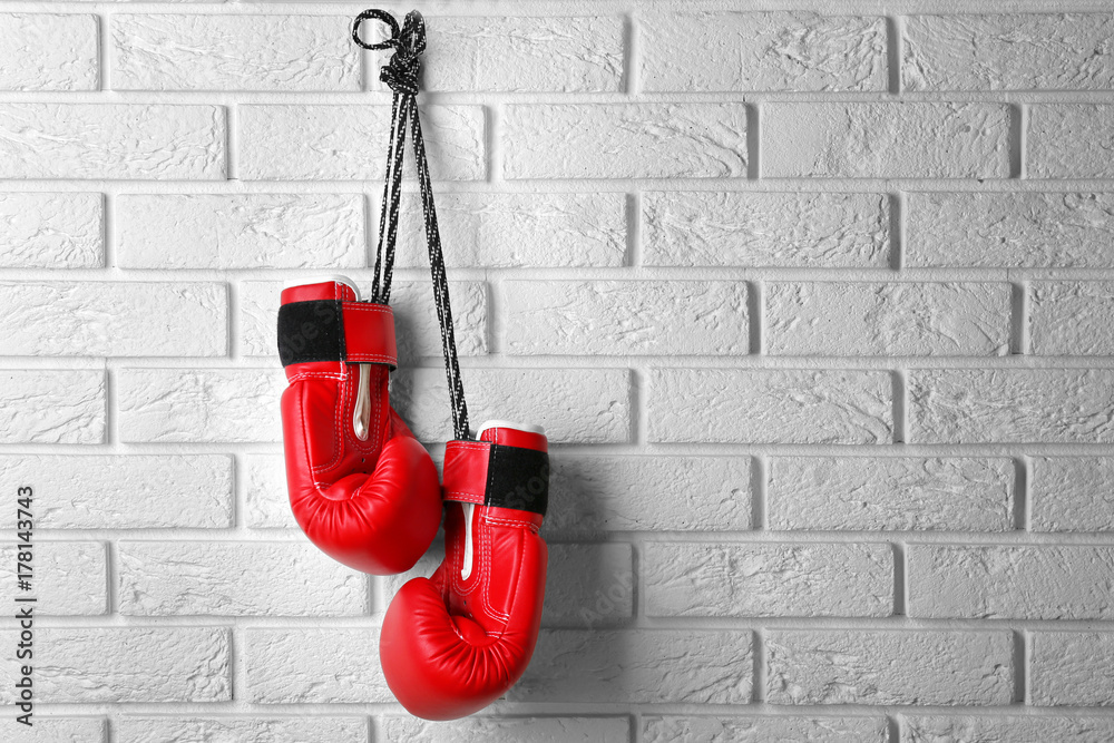 Fototapeta Pair of red boxing gloves hanging on brick wall