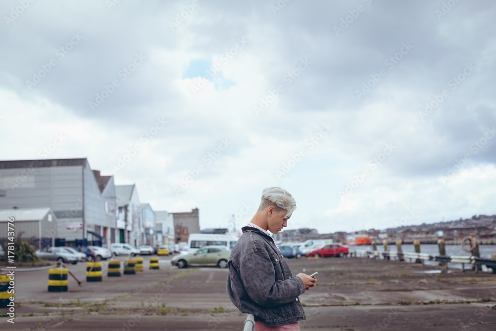 Side view of man using mobile phone while standing outdoors Side view of man using mobile phone while standing outdoors