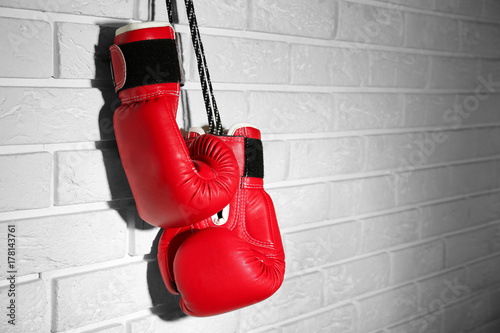 Pair of red boxing gloves hanging on brick wall © Africa Studio