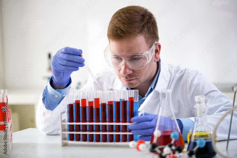 Concentrated chemist holding pipette and working at laboratory Concentrated chemist holding pipette and working at laboratory