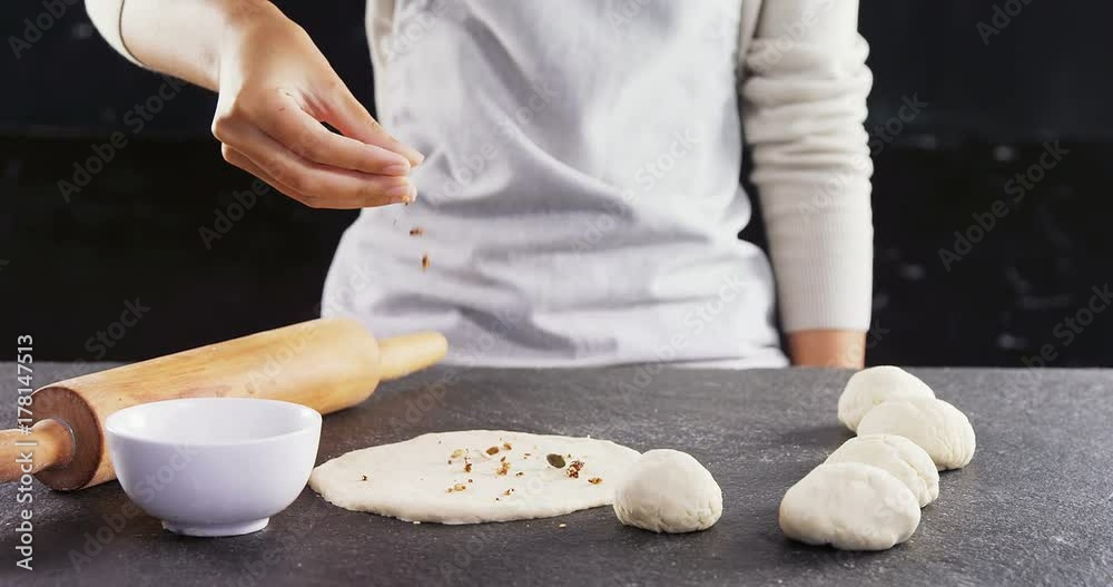 Woman adding dry fruits over flattened dough 