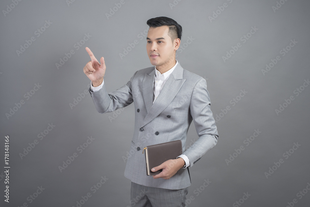 Businessman is touching virtual screen, portrait in studio grey background Businessman is touching virtual screen, portrait in studio grey background