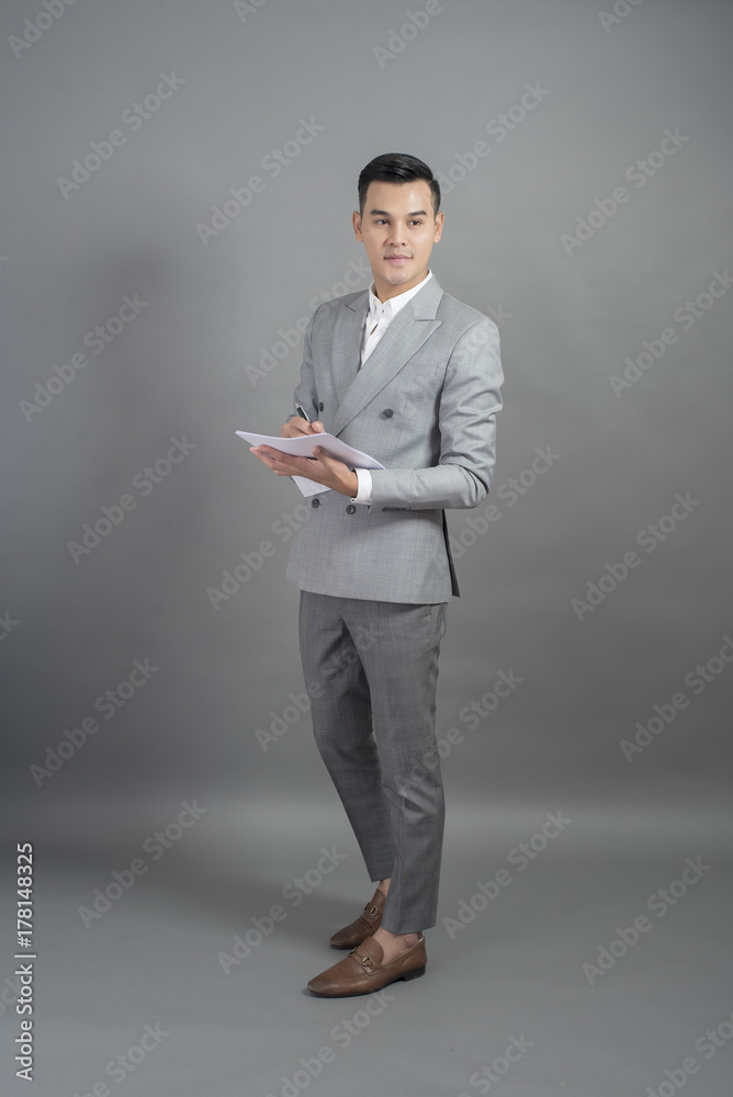 Businessman is writing business goal, grey background Businessman is writing business goal, grey background