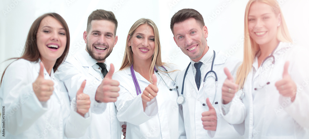 Smiling team of doctors at hospital making selfie and showing th Smiling team of doctors at hospital making selfie and showing th