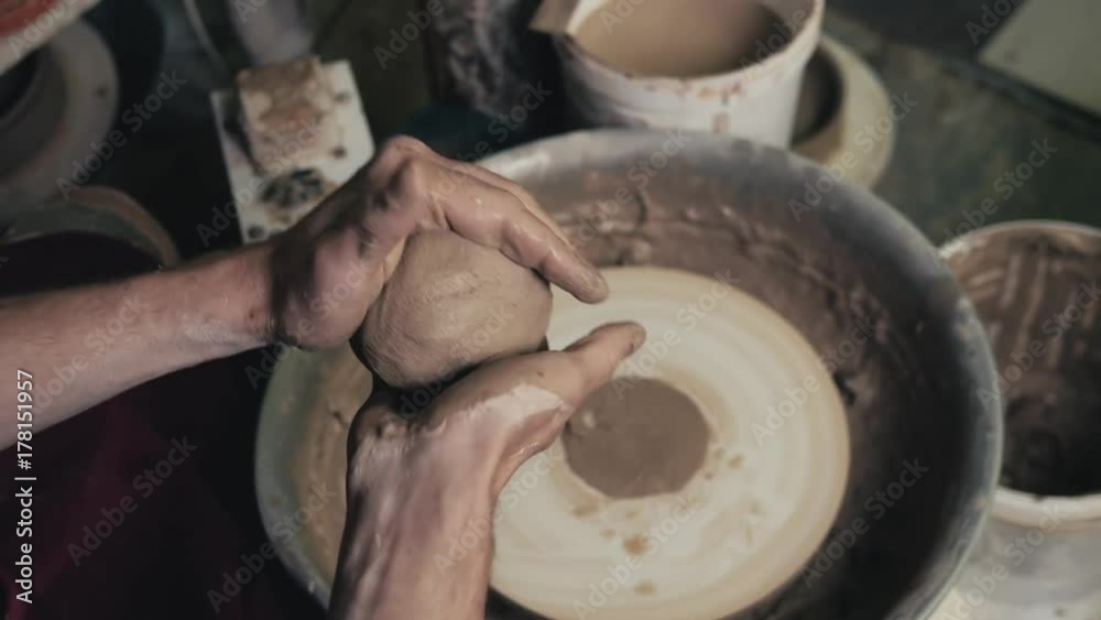 Potter shapes the clay product with pottery tools on the potter's wheel