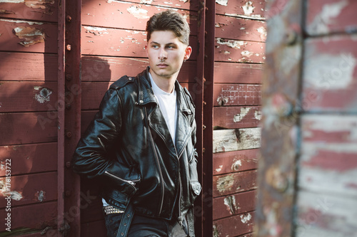Young punk rocker standing against the old train wagon