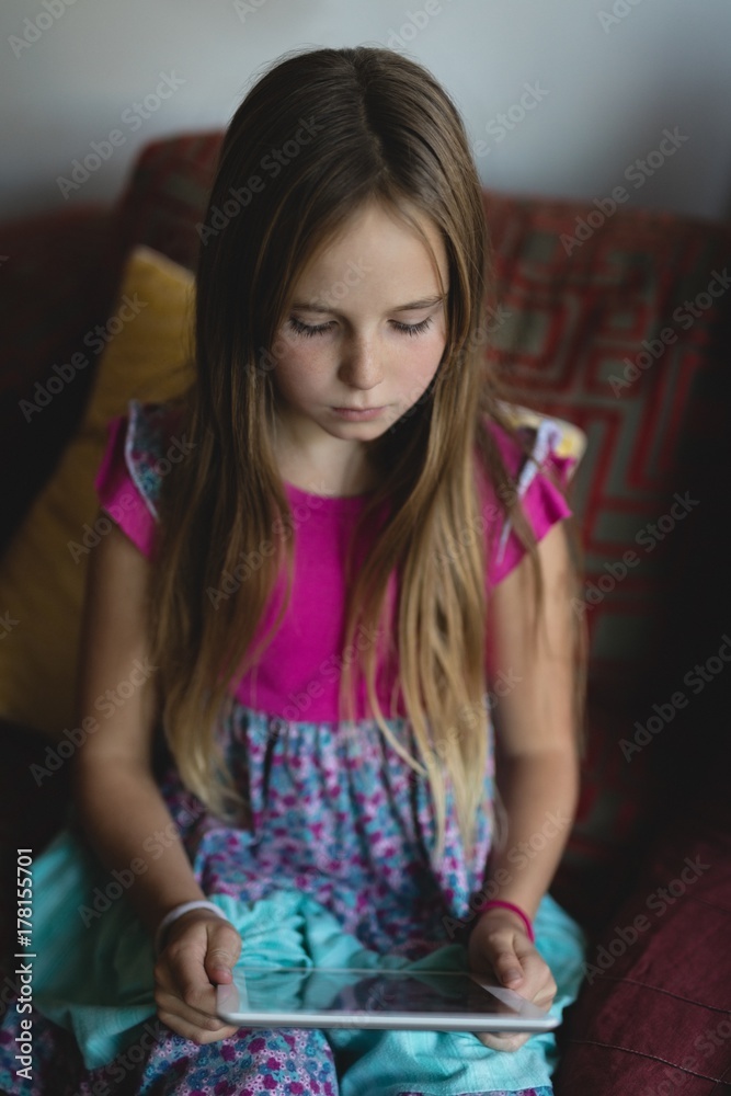 Girl using digital tablet on sofa in living room Girl using digital tablet on sofa in living room