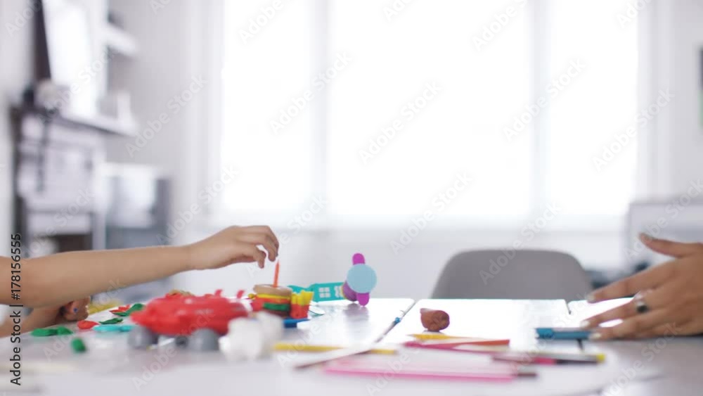 Young adult female using a digital tablet as a child plays on the table in front of her Young adult female using a digital tablet as a child plays on the table in front of her
