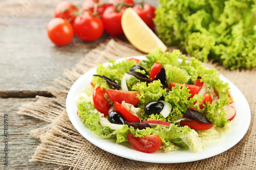 Fresh salad with vegetables on wooden table