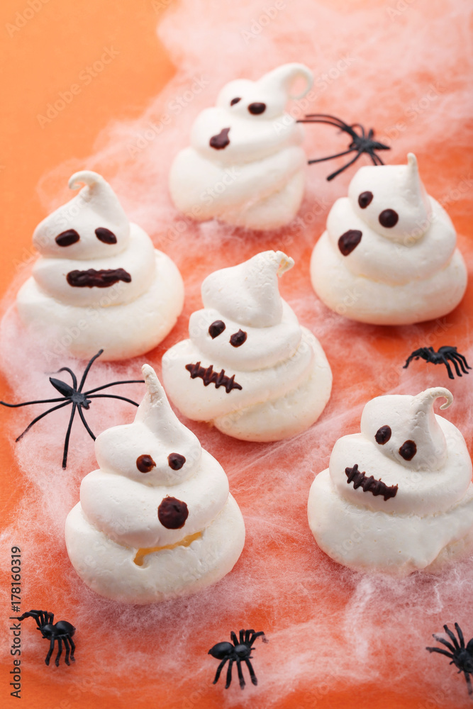 Halloween meringue with spiders on orange background Halloween meringue with spiders on orange background