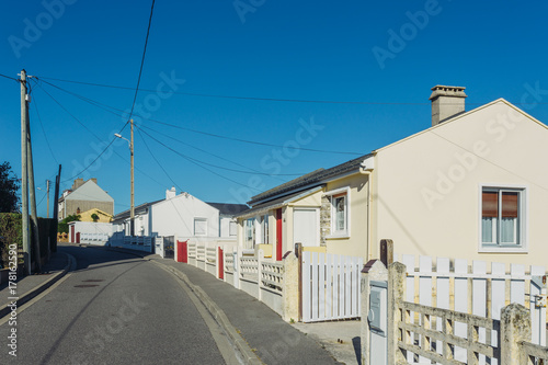 Fototapeta Naklejka Na Ścianę i Meble -  Country houses with white fences and streets in the region of Normandy, France on a sunny day. Countryside, lifestyle and typical french architecture, european country landscapes.