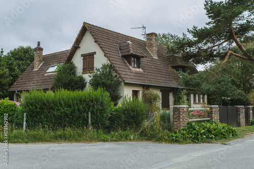 Fototapeta Naklejka Na Ścianę i Meble -  Country houses with green fences and streets in the region of Normandy, France. Beautiful countryside, lifestyle and typical french architecture, european country landscapes.