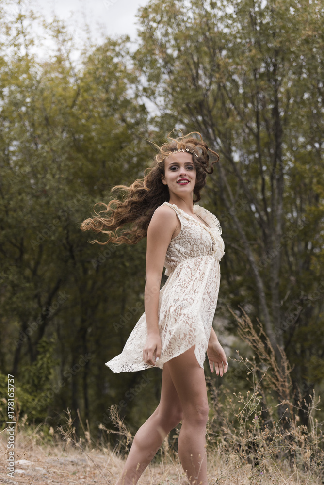 Young woman with long curly hair wear handmade look dress with intricate patterns, pose in forest Young woman with long curly hair wear handmade look dress with intricate patterns, pose in forest