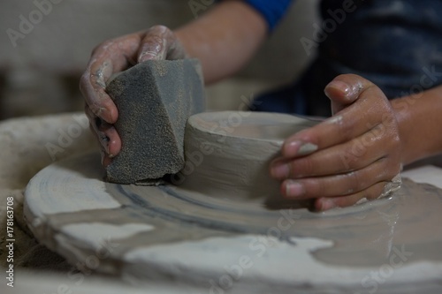 Girl using sponge while molding a clay photo