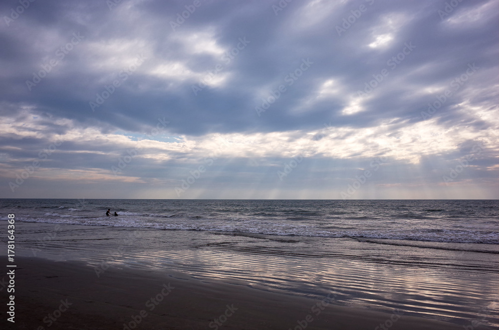 silhouettes of two people having fun in the ocean at sunset