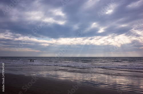 silhouettes of two people having fun in the ocean at sunset