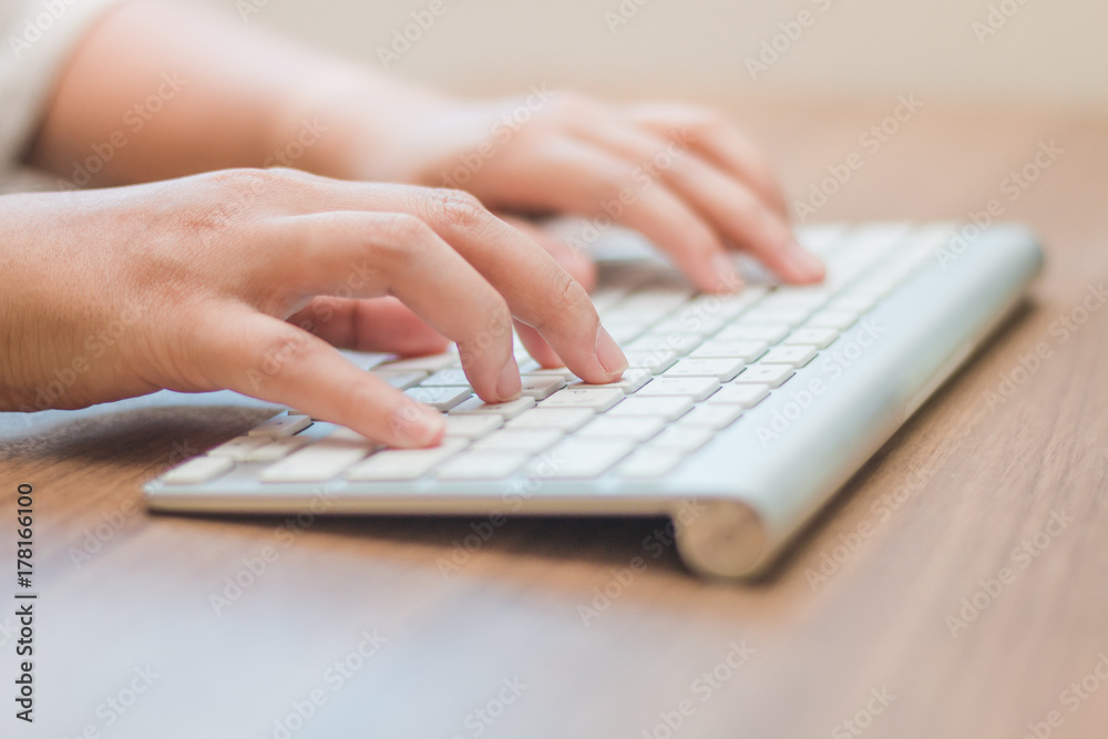 Close-up hand typing white keyboard on wooden table Close-up hand typing white keyboard on wooden table
