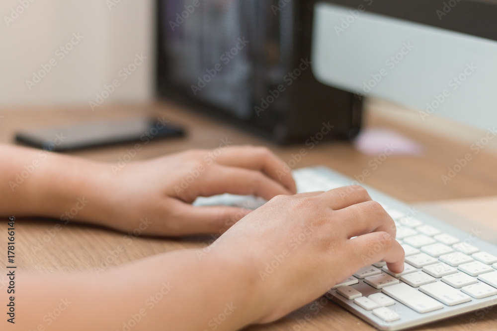 Close-up hand typing  white keyboard on wooden table