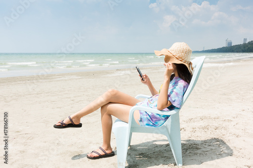 woman with hat relax in the sun on their deck chairs in the beach. Traveling, vacation, concept.