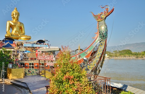 Золотой сидячий Будда в лодке на берегу меконга в храме Phra Chiang Saen Si Phaendin