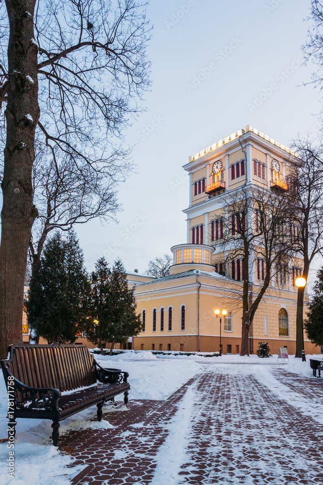 Winter alley with a bench and a clock tower in the park