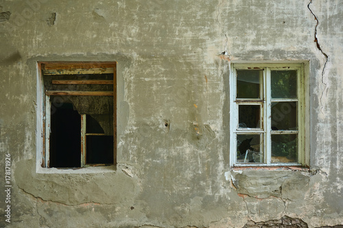 The old dirty broken window on the old dirty wall with cracks.