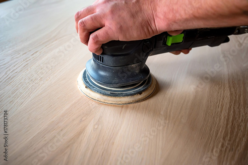 Photography Man sanding wood with orbital sander in a workshop
