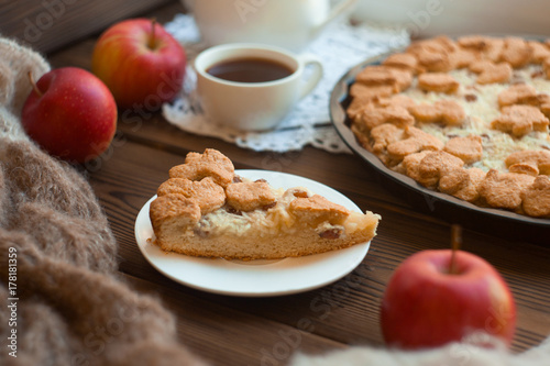 Popular American apple pie piece and cup of tea on wooden table background. Homemade classical fruit tart