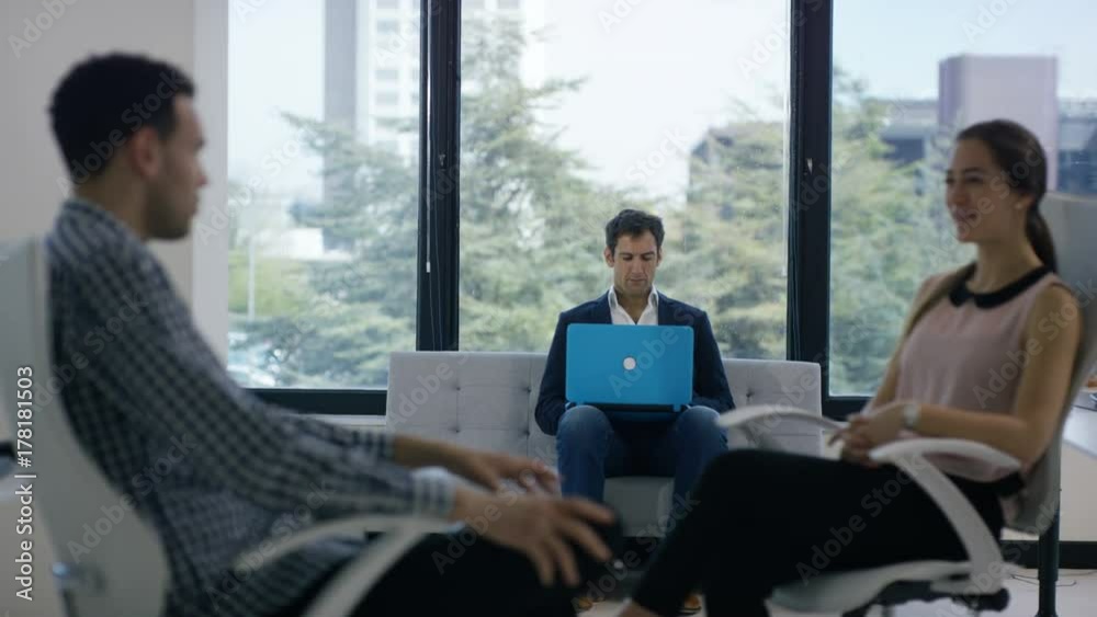 Business team talking in modern office, looking at graphs on computer tablet Business team talking in modern office, looking at graphs on computer tablet