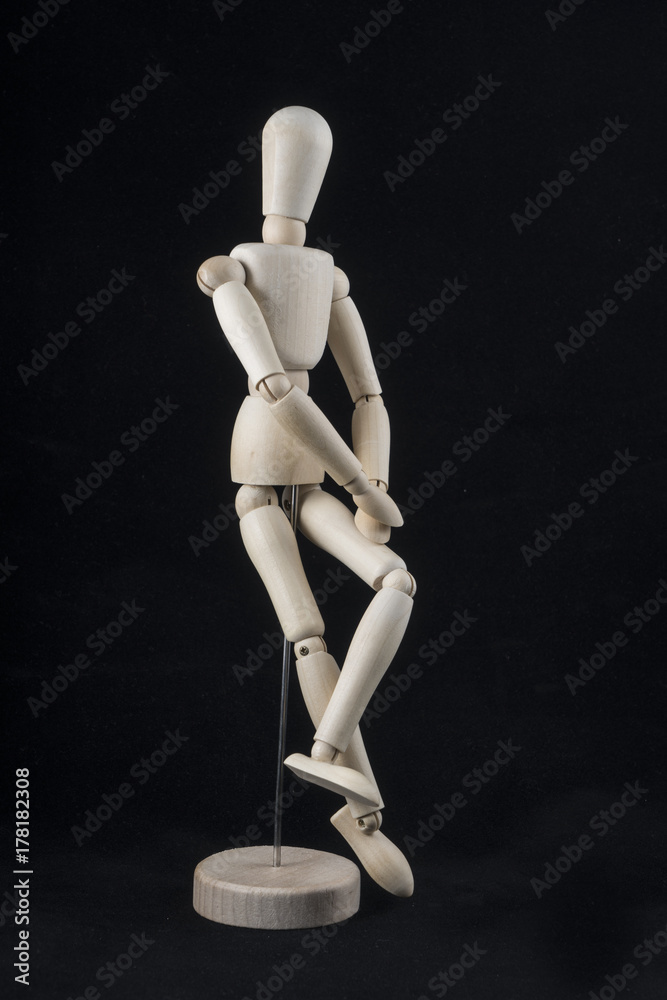 a wooden mannequin in sitting position with a black background a wooden mannequin in sitting position with a black background
