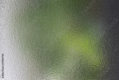 Abstract glass texture with blur of green tree view.