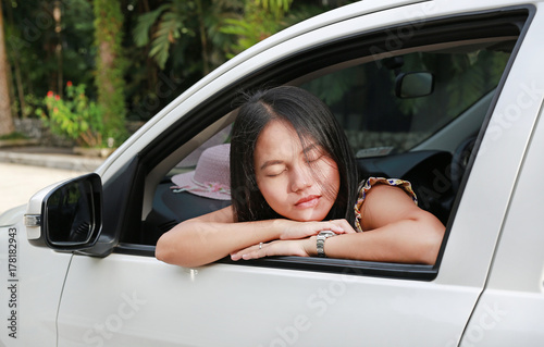 Young Asian woman sleeping at the window of a white car. © zilvergolf