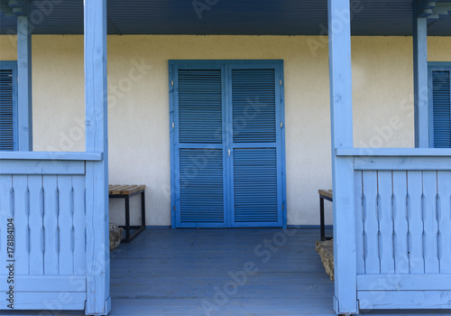 White house with light blue door, window and terrace. Traditional Greek style architecture influence 