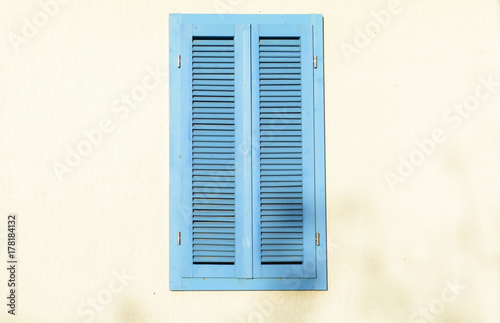 Close up photo of a blue window in the sunlight. Nature view greek style window on white concrete wall color