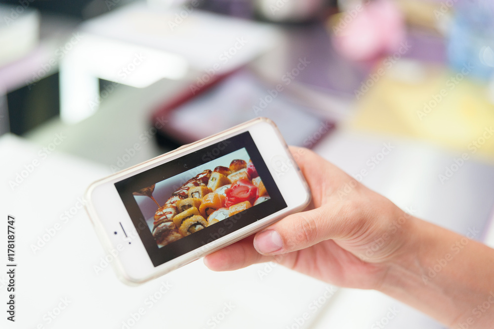 Hands taking photo sushi with smartphone