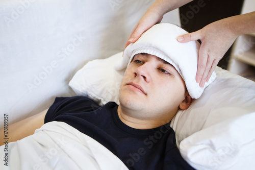 A sick male sleeping with wet towel on his forehead to reduce high high fever